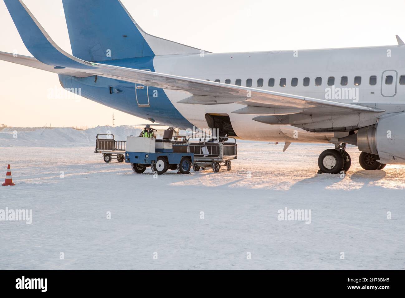 baggage loading at airport in winter. Luggage in carts near aircraft in winter. Passenger aircraft in winter at airport loaded baggage before departur Stock Photo