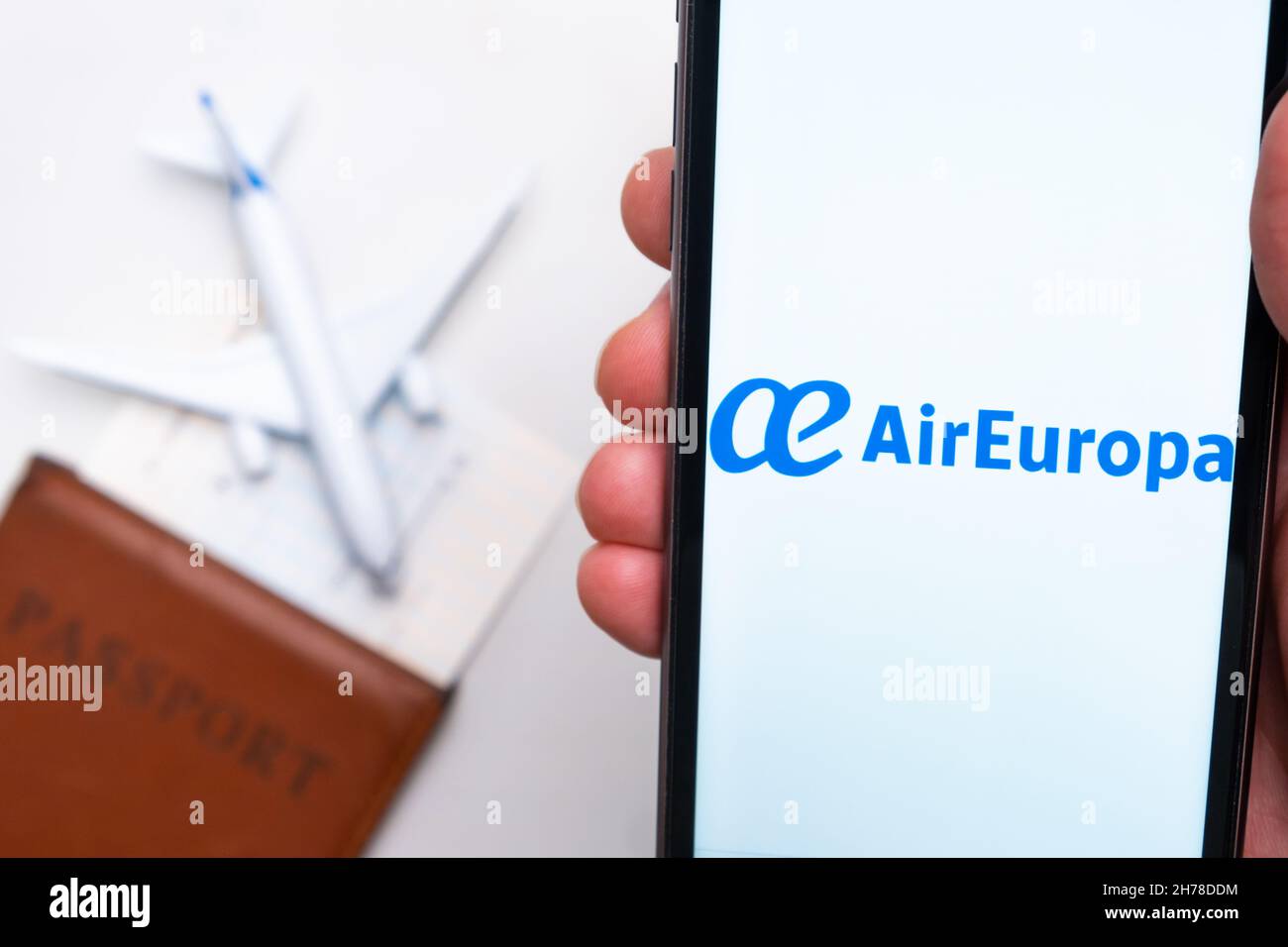 AirEuropa Airline app on a smartphone screen in mans hand. A toy plane, passport and tickets are on the table. November 2021, San Francisco, USA Stock Photo