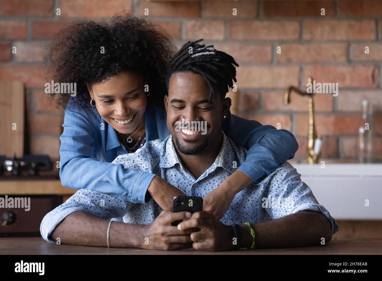 Happy biracial couple using smartphone apps at home. Stock Photo