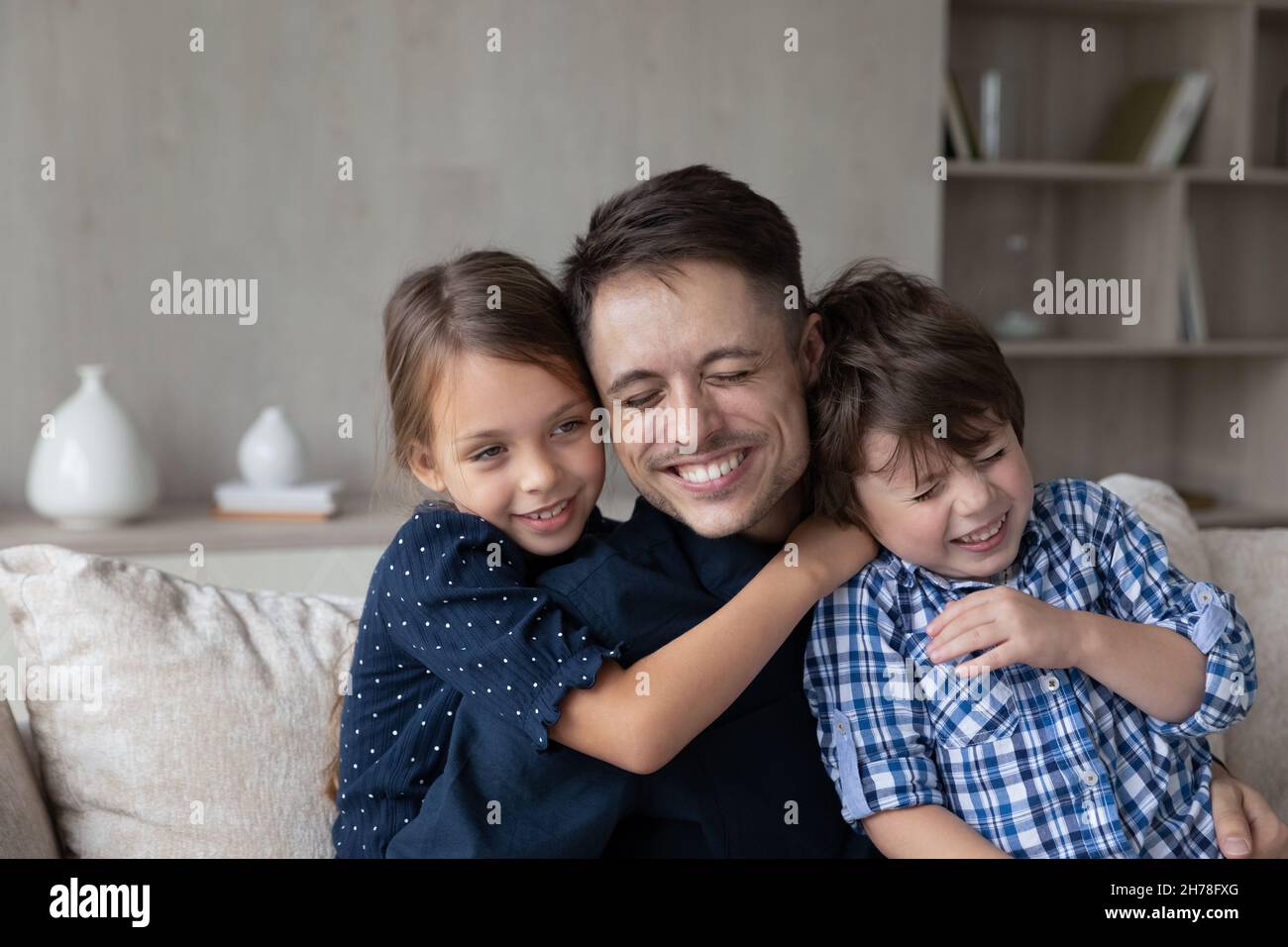 Loving son and daughter cuddling young cheerful daddy Stock Photo