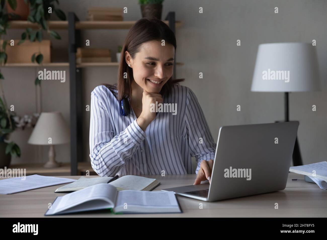 Smiling attractive young woman web surfing educational information online. Stock Photo