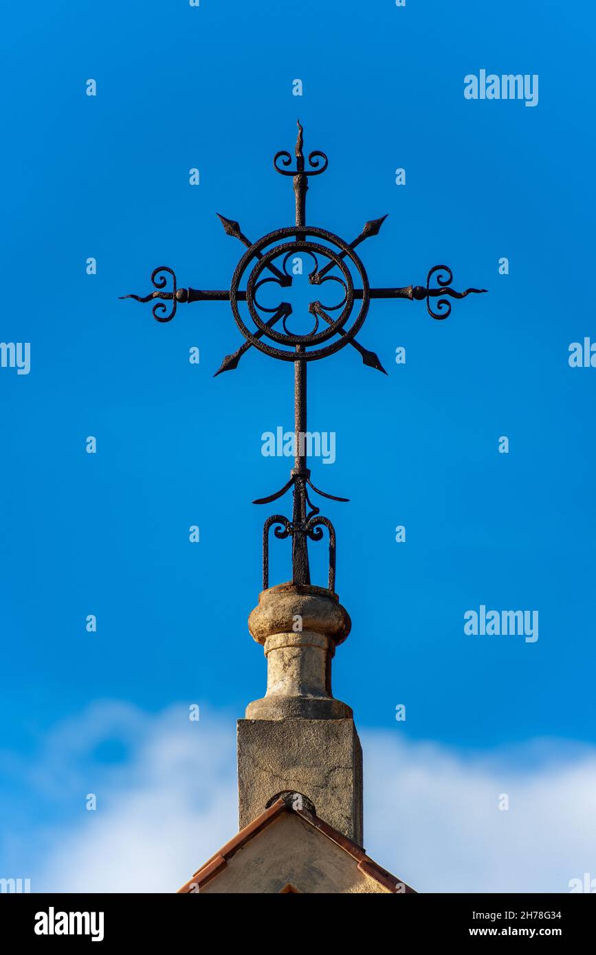 Detail of a wrought iron cross on a blue sky with clouds, Christian religious symbol. Church of the Sacred Heart in La Spezia, Liguria, Italy. Stock Photo