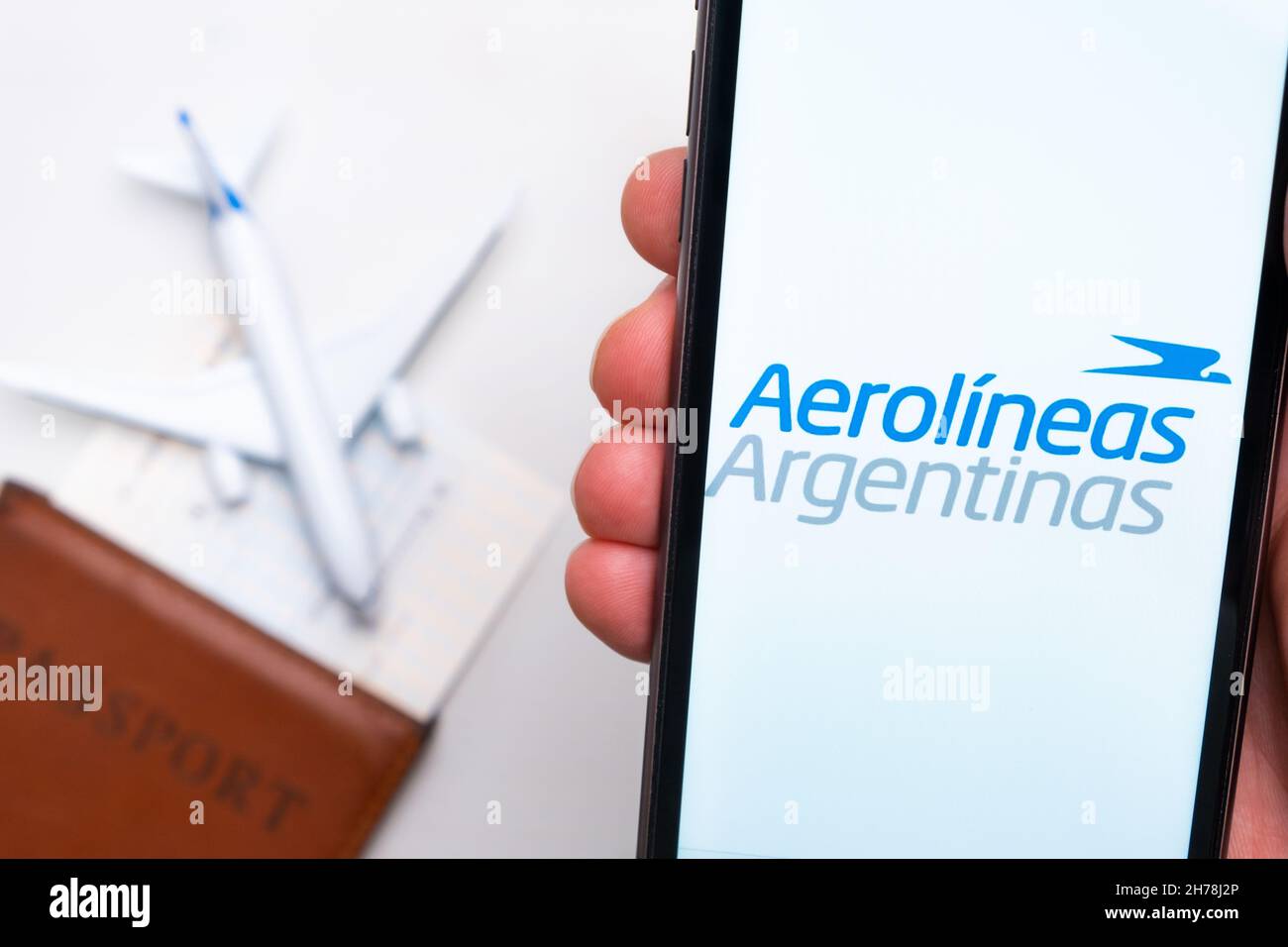 Aerolineas Argentinas Airline application on the screen of mobile phone in mans hand. Passport, boarding bass are next to a white plane on the background. November 2021, San Francisco, USA Stock Photo