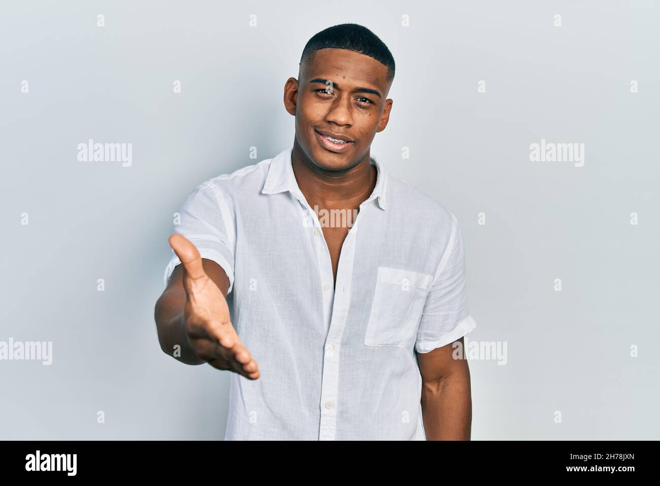 Young black man wearing casual white shirt smiling friendly offering ...