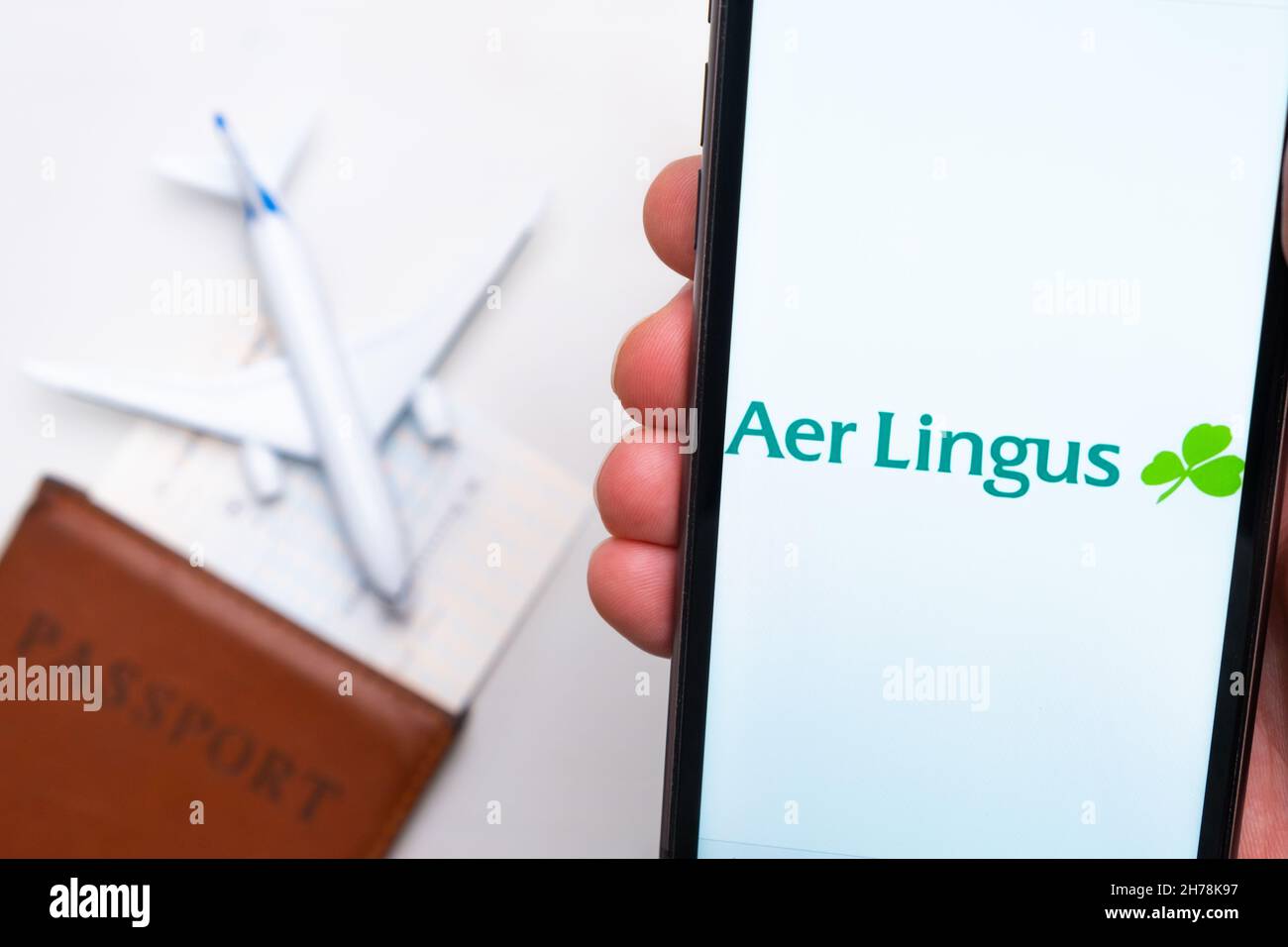 Aer Lingus Airline application on the screen of mobile phone in mans hand. Passport, boarding bass are next to a white plane on the background. November 2021, San Francisco, USA Stock Photo