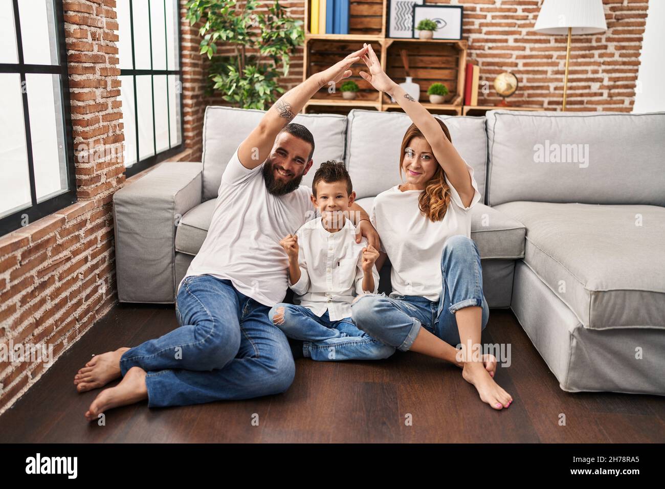 Family of three doing house shape with arms screaming proud, celebrating victory and success very excited with raised arm Stock Photo