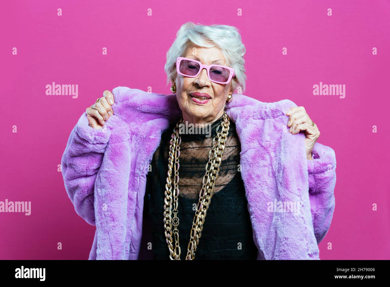 image of a beautiful and elegant old influencer woman. Cool grandmother posing in studio wearing fashionable clothes. Happy senior lady celebrating an Stock Photo