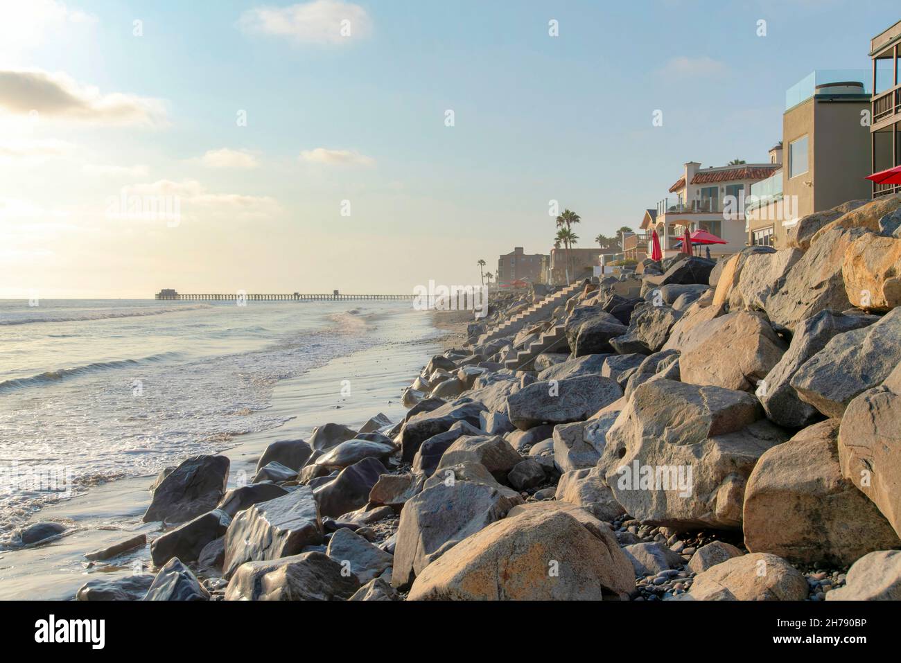 Beach with natural rock seawall and a view of a pier at Oceanside ...