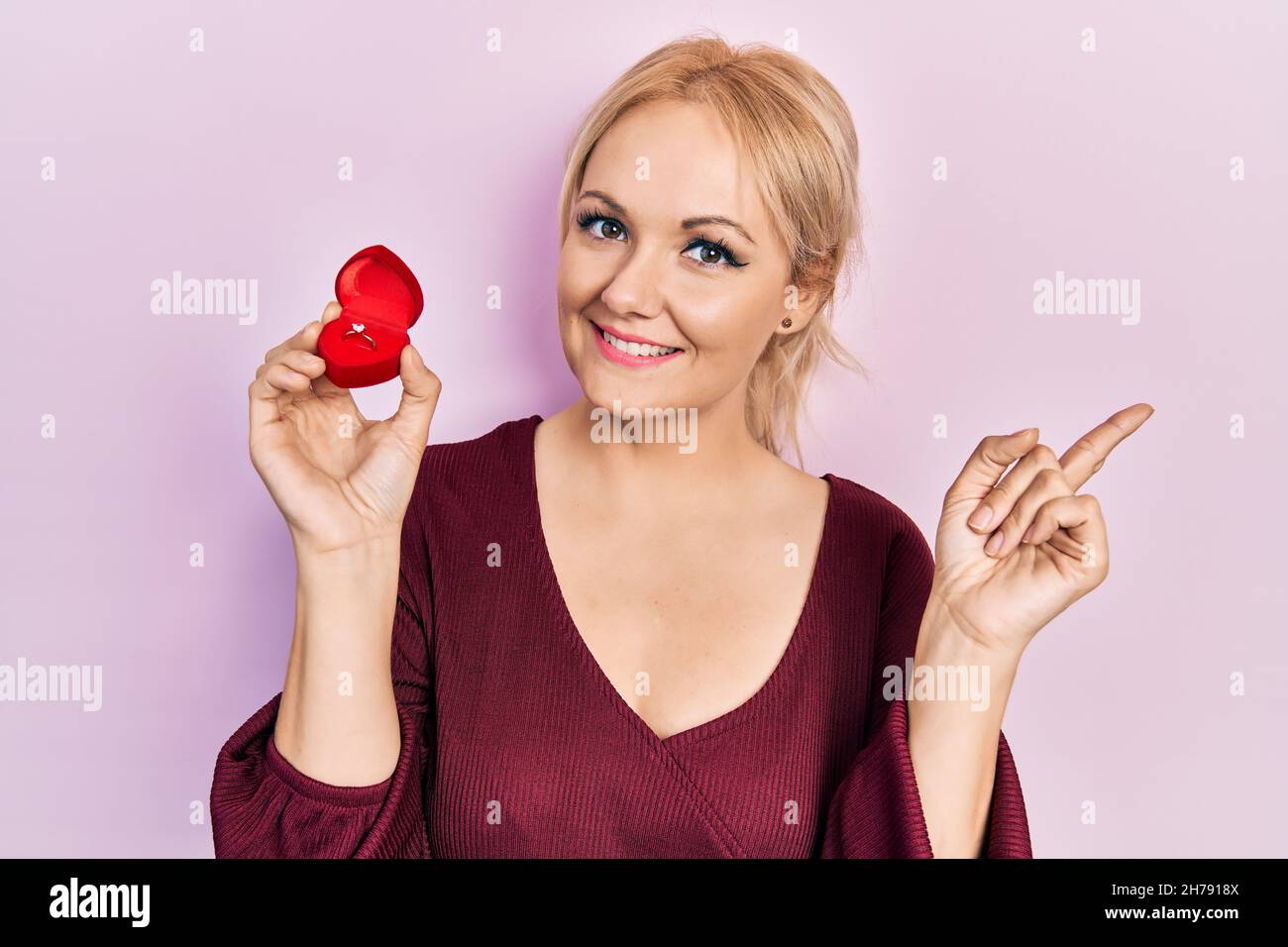 Young blonde woman wearing engagement ring smiling happy pointing with ...