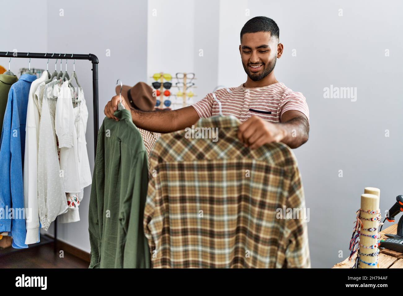 Young arab man holding shirt shopping at clothing store Stock Photo - Alamy