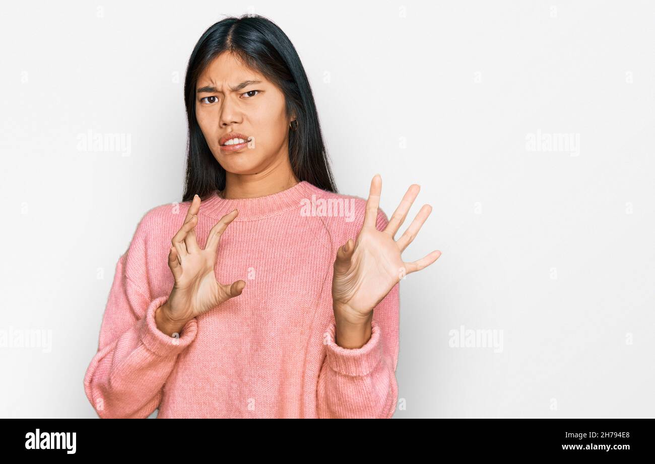 Beautiful young asian woman wearing casual winter sweater disgusted expression, displeased and fearful doing disgust face because aversion reaction. w Stock Photo