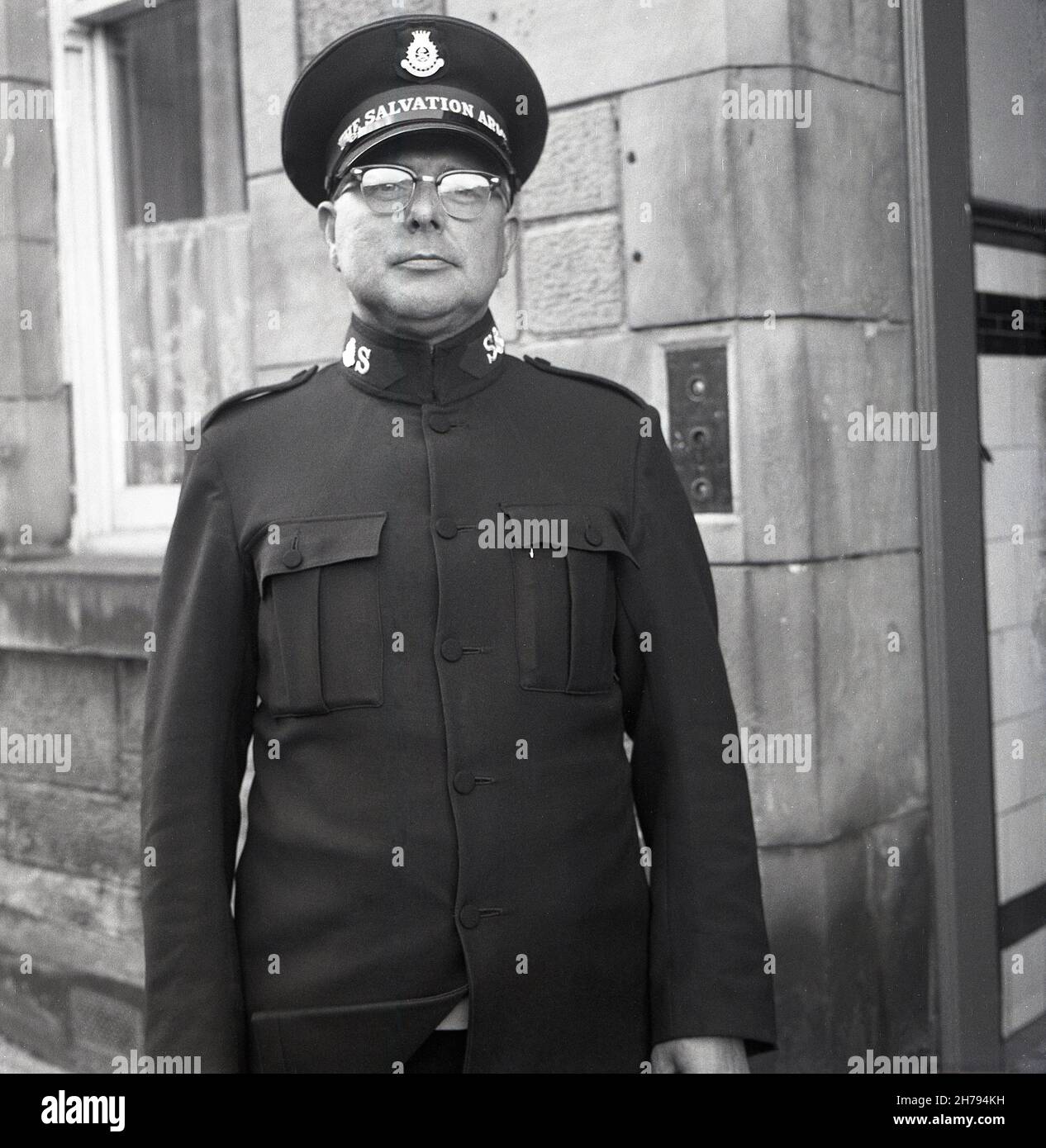 1965, outside a building, a soldier of The Salvation Army in his uniform and hat proudly standing upright for his photo, Fife Scotland, UK. Soldiers of The Salvation Army are Christians who have undertaken a specific convenant or promise regarding lifestyle and beliefs and wear the uniform as a visible sign of their faith. Officers, Soldiers and Adherents are known as Salvationists. Founded in London in 1865 by William Booth and wife, Catherine as a charity to bring 'Salvation' to the poor & destitute, Booth introduced the military structure in 1878, which continued as a matter of tradition. Stock Photo