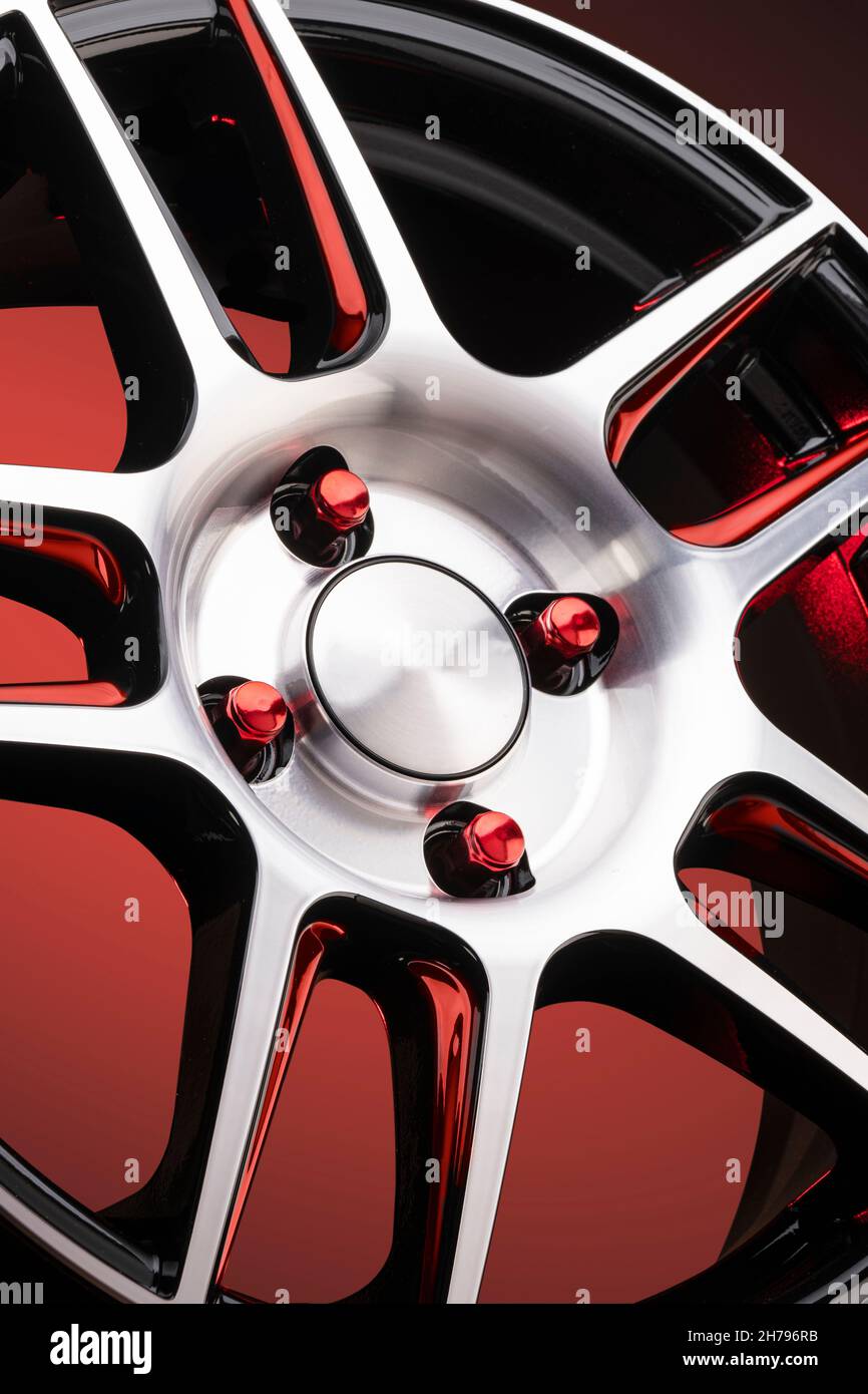 a fragment of red alloy wheels, spokes, wheel nuts and details of a