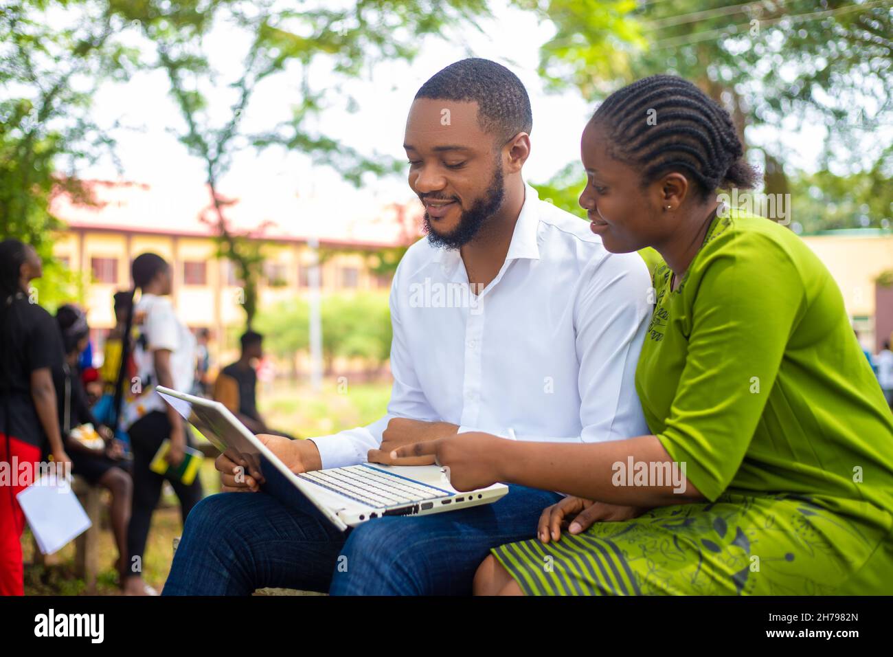Young African male and a female watching something on a laptop with ...