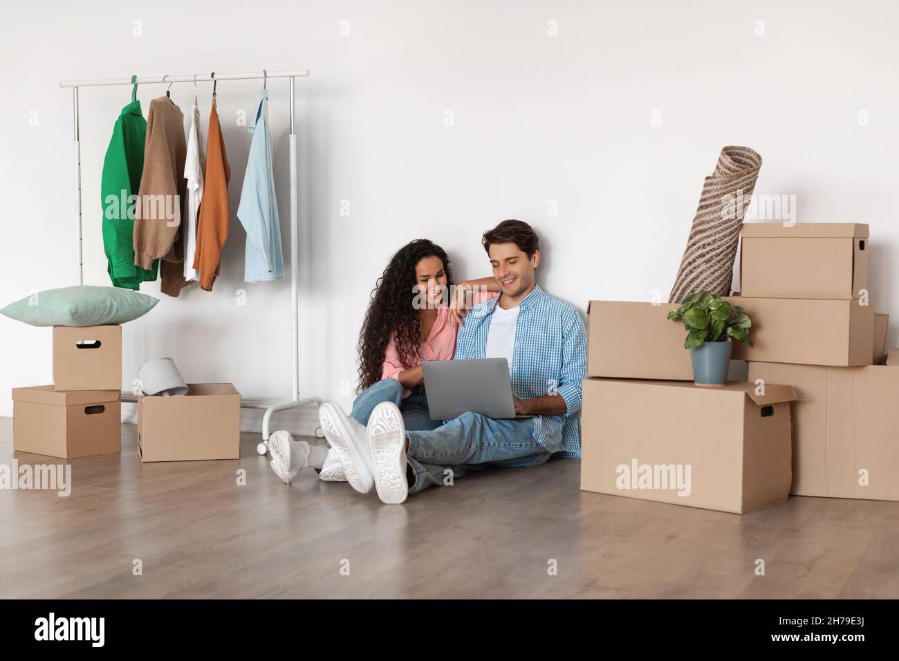 Happy millennial couple using laptop after relocation Stock Photo