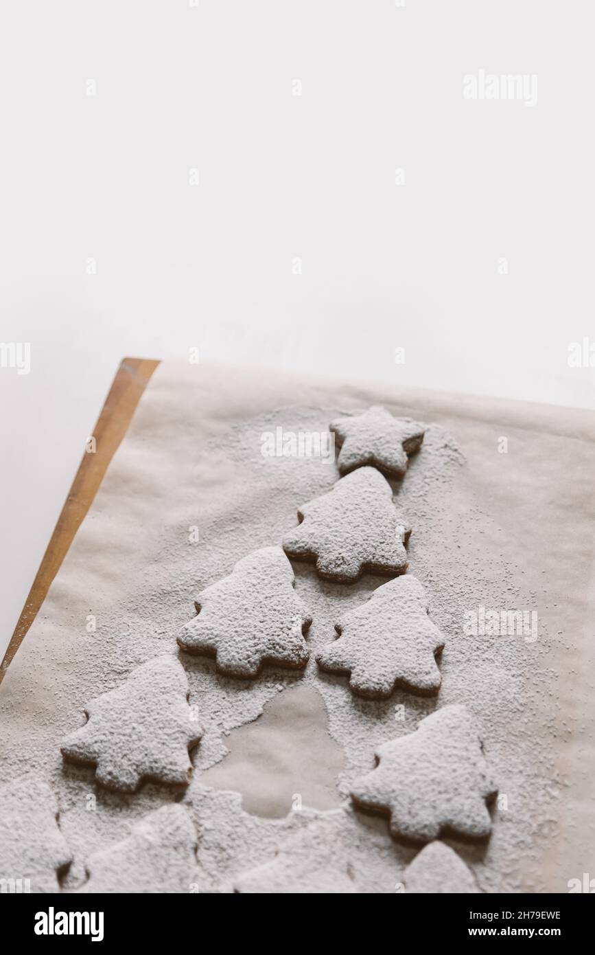 Gingerbread Christmas tree sprinkled with powdered sugar on parchment. Creative composition, close-up, copy space, top view Stock Photo