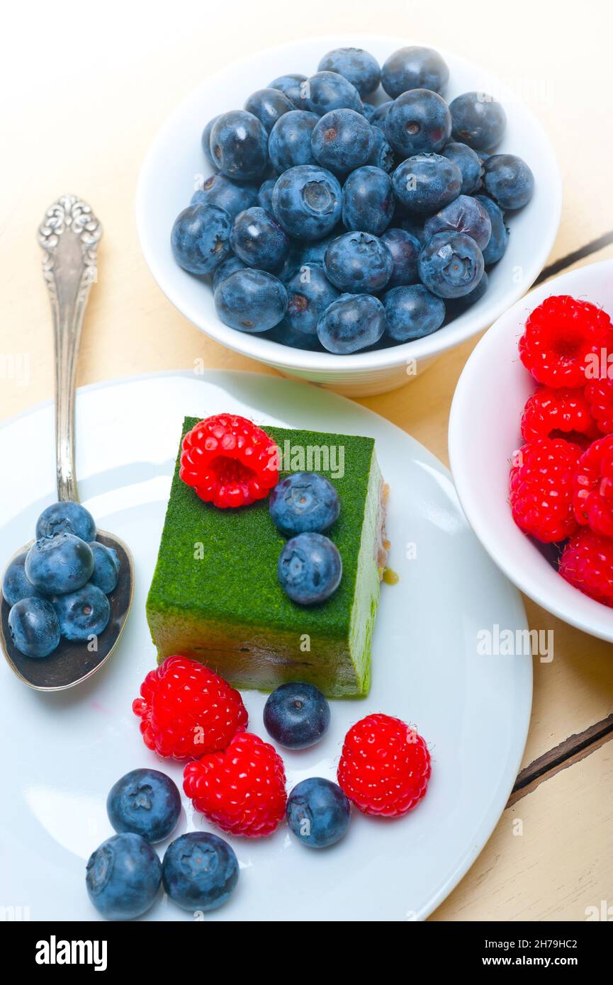green tea matcha mousse cake with raspberries and blueberries on top Stock Photo
