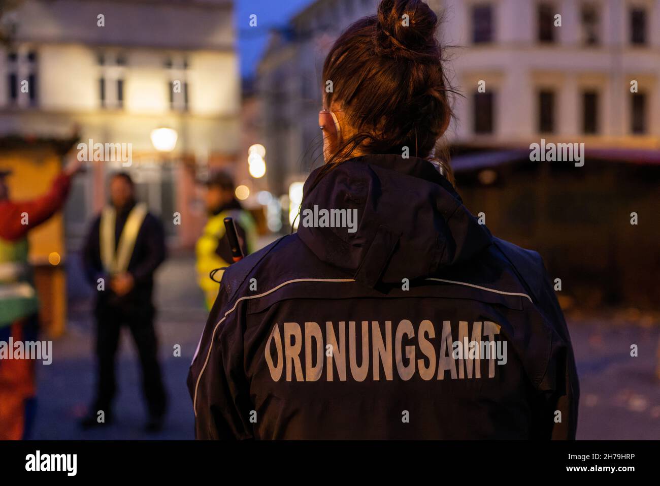 Cottbus, Germany. 19th Nov, 2021. An employee of the Cottbus public order office walks through the Christmas market that is being set up. A joint patrol consisting of employees of the Public Order Office and police officers of the Cottbus/Spree-Neiße police inspection checks the enforcement of the provisions of the SARS-CoV-2 Containment Ordinance in Cottbus city centre. Credit: Frank Hammerschmidt/dpa-Zentralbild/dpa/Alamy Live News Stock Photo