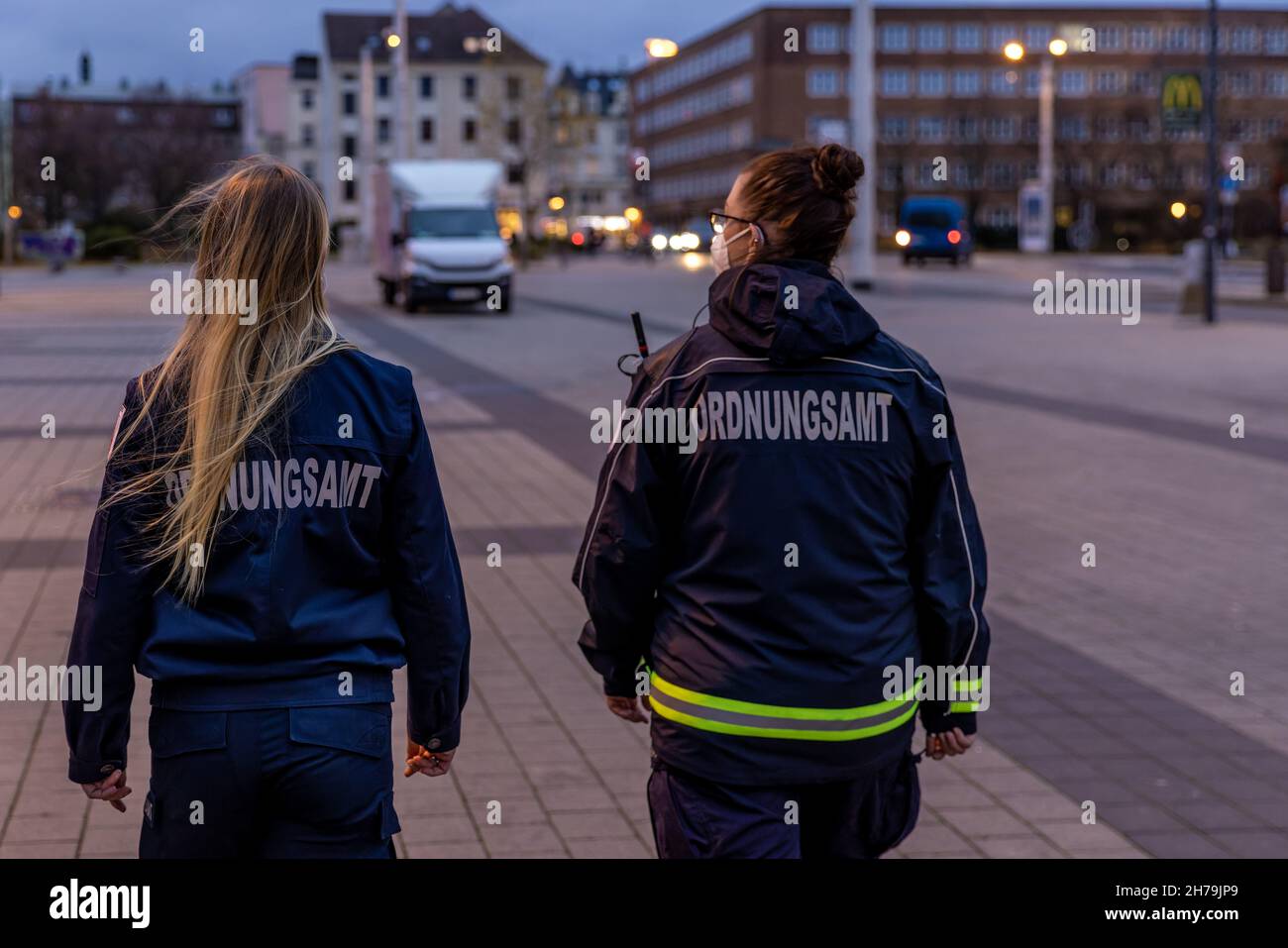 Cottbus, Germany. 19th Nov, 2021. Employees of the public order office walk across Berliner Platz. A joint patrol consisting of employees of the Public Order Office and police officers of the Cottbus/Spree-Neiße police inspection checks the enforcement of the provisions of the SARS-CoV-2 Containment Ordinance in Cottbus city centre. Credit: Frank Hammerschmidt/dpa-Zentralbild/dpa/Alamy Live News Stock Photo