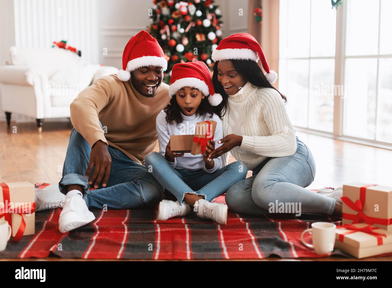Surprised black girl celebrating Christmas unwrapping gift box Stock Photo
