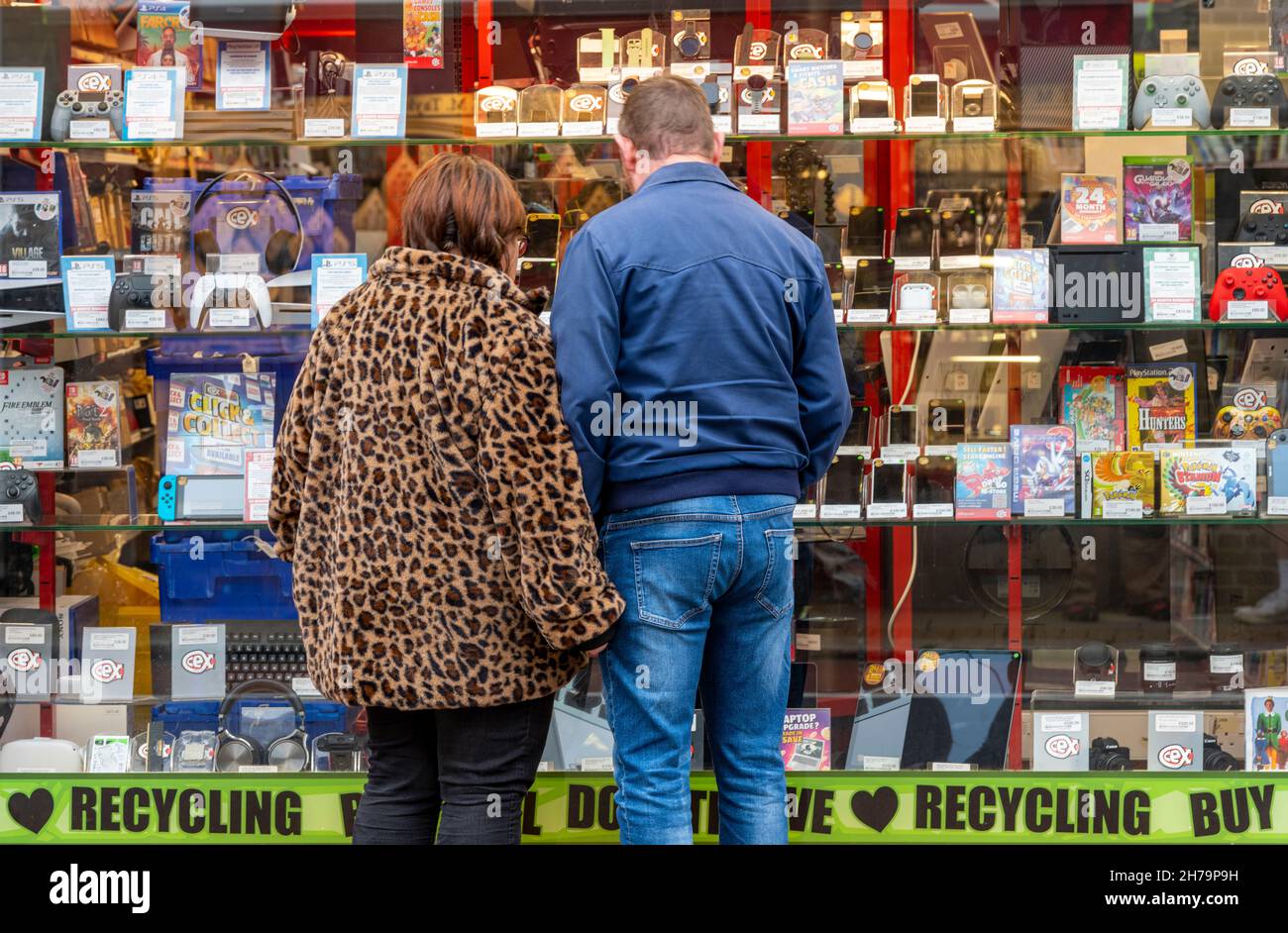 couple looking in the window of an electrical recycler shop or electronics and technology exchange store, mobile phones and smartphones pawn shop. Stock Photo