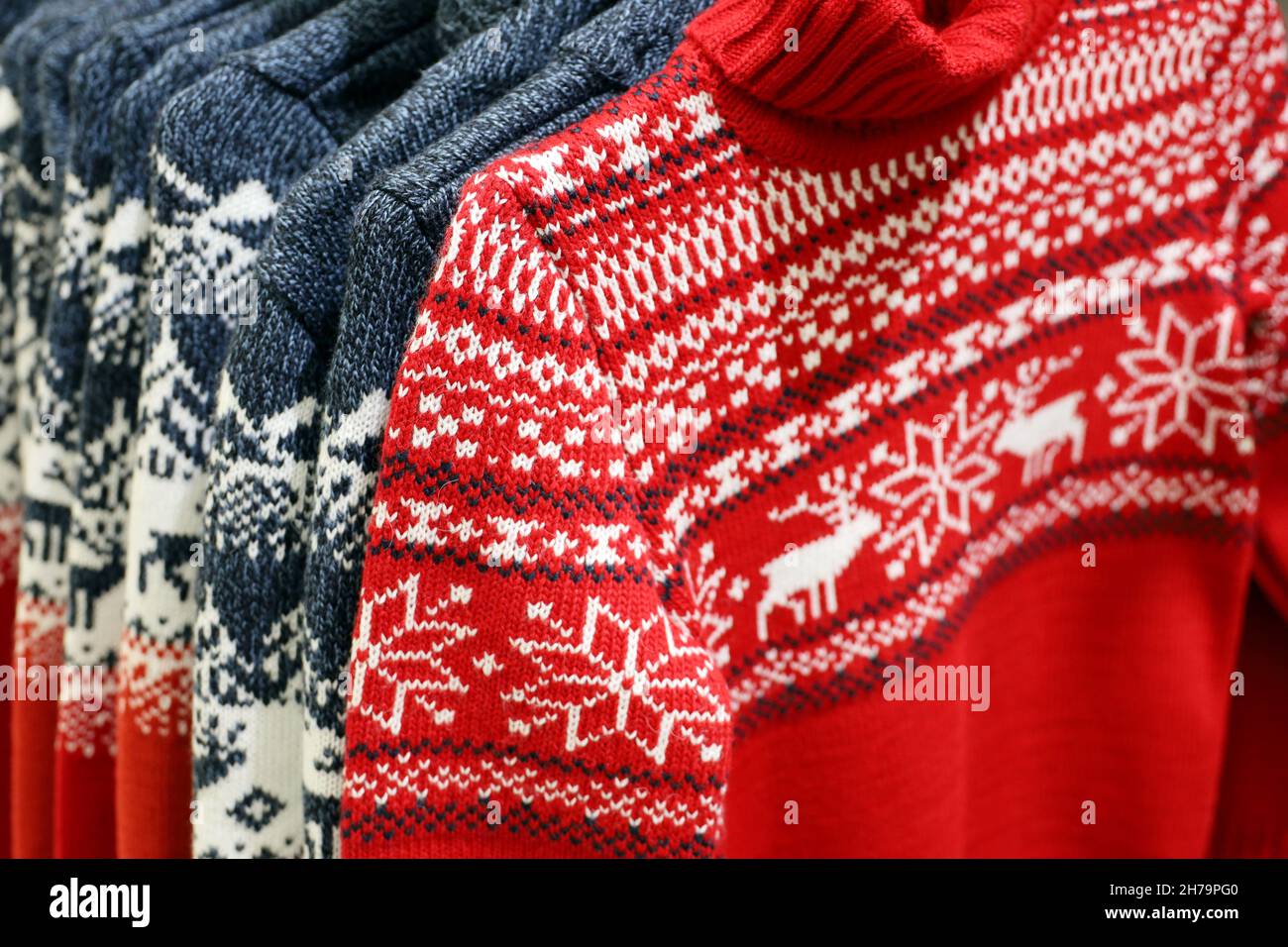 Knitted sweaters with Christmas pattern in a store. Traditional warm outfit for New Year holidays Stock Photo