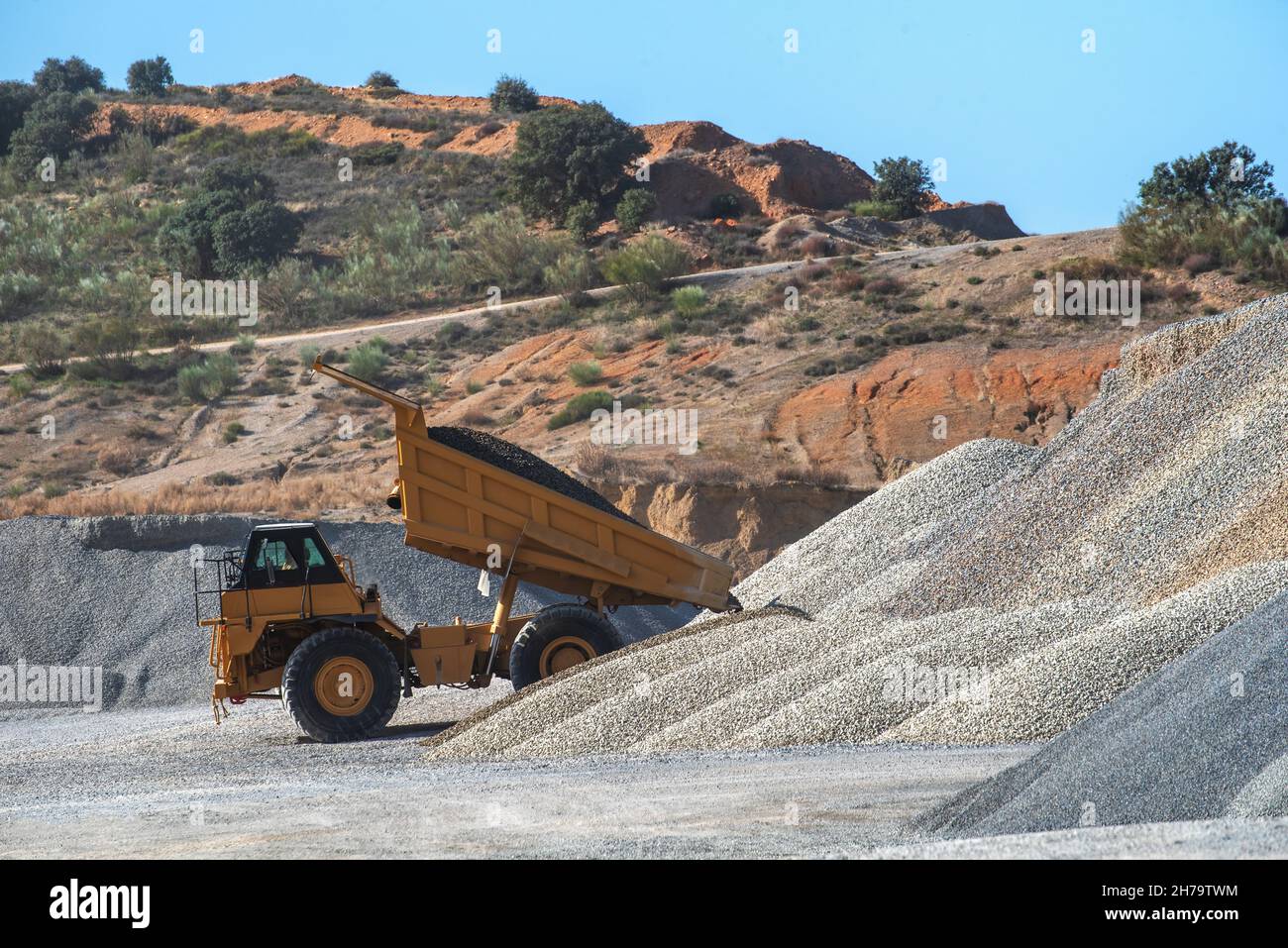 Large dump truck with the tipper raised unloading sand in a quarry. Stock Photo