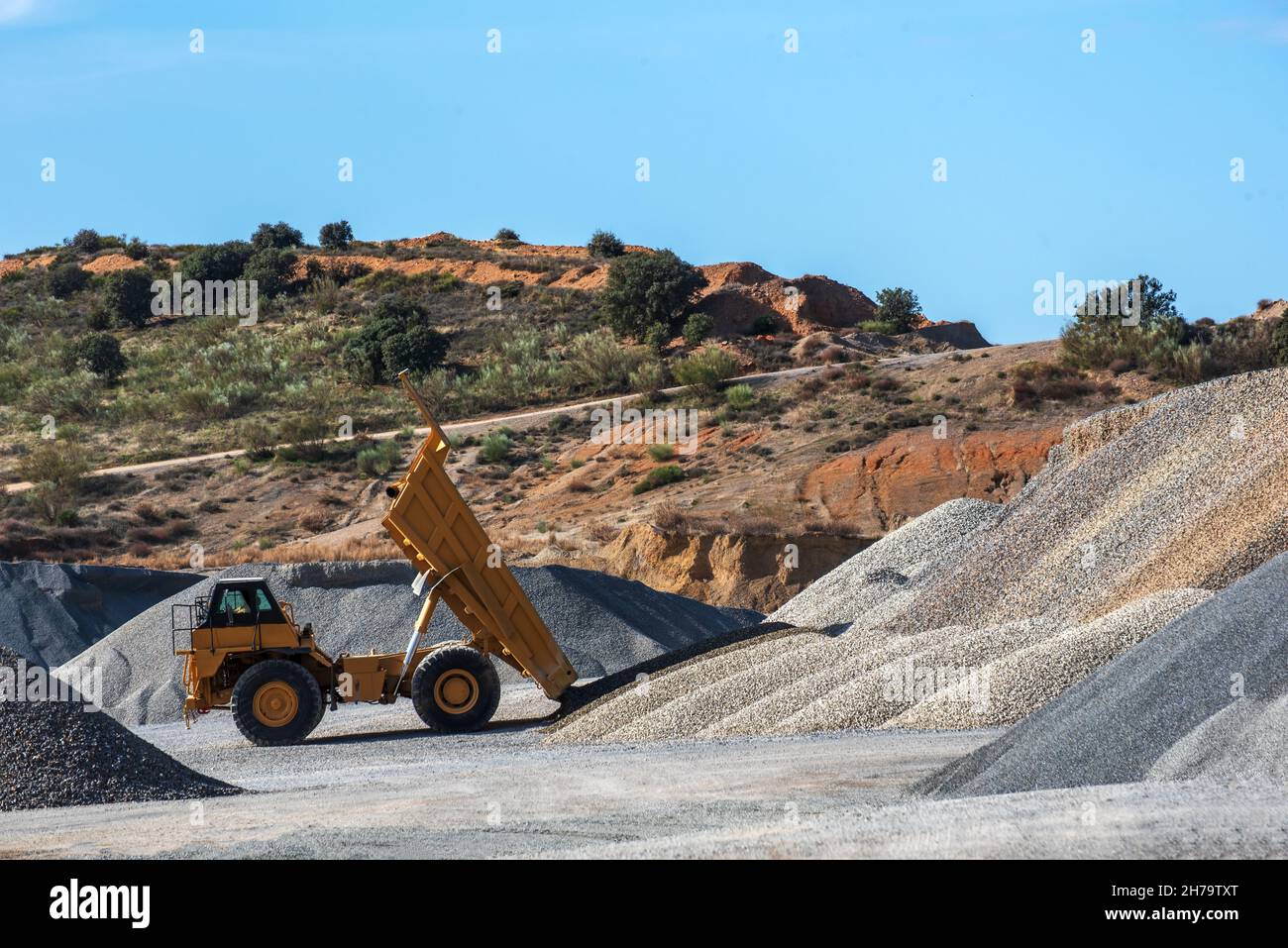 Large dump truck with the tipper raised unloading sand in a quarry. Stock Photo