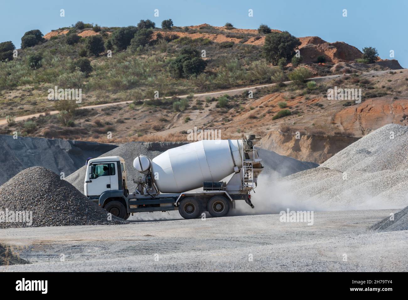 Concrete mixer truck driving between mountains of sand and gravel in a quarry. Stock Photo