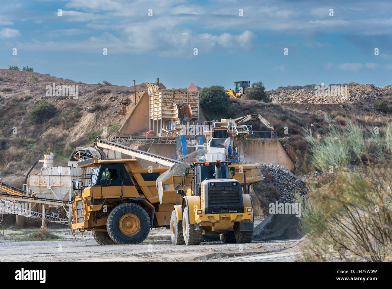 Excavator shovel loading a large dump truck in a sand and gravel quarry. Stock Photo