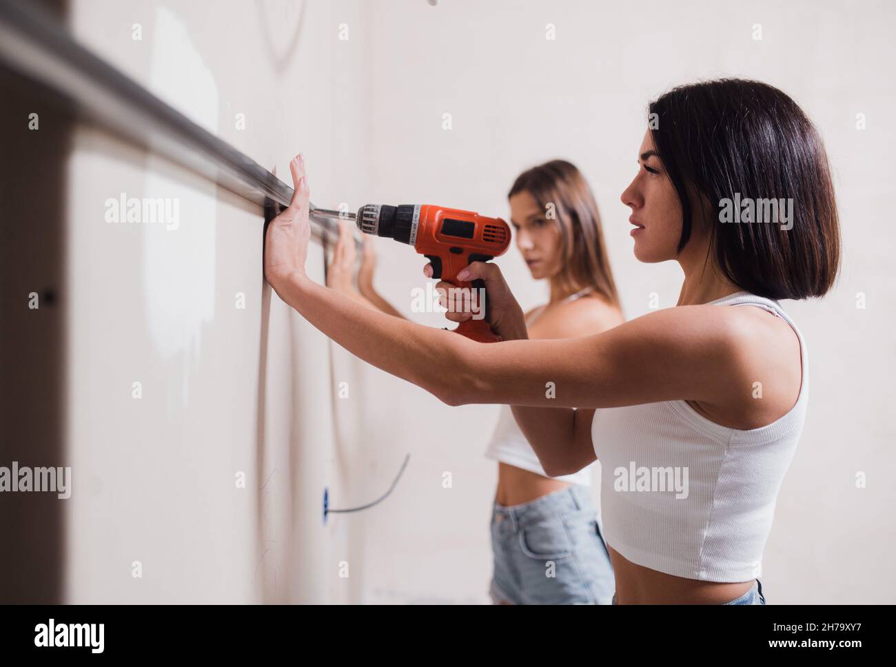 young women make repairs in the apartment. Two girls make repairs at home on their own Stock Photo