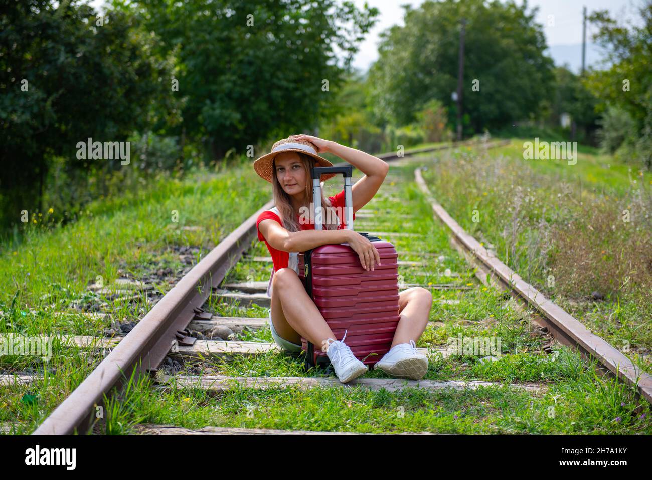 the traveler sits on the rails with a suitcase Stock Photo - Alamy