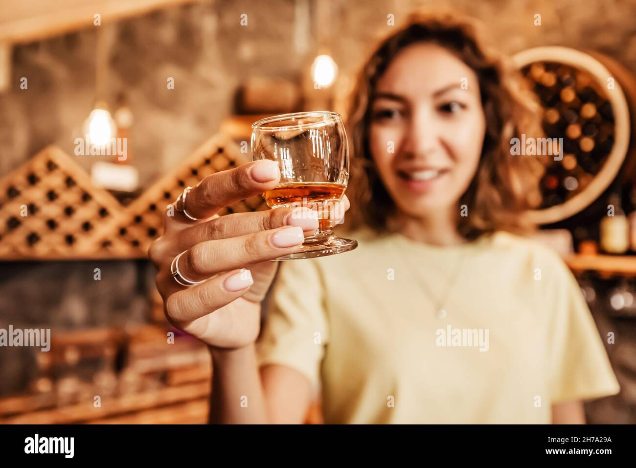 Happy asian woman tastes a new brand of cognac from a glass at the winery. The concept of strong alcohol and brandy Stock Photo