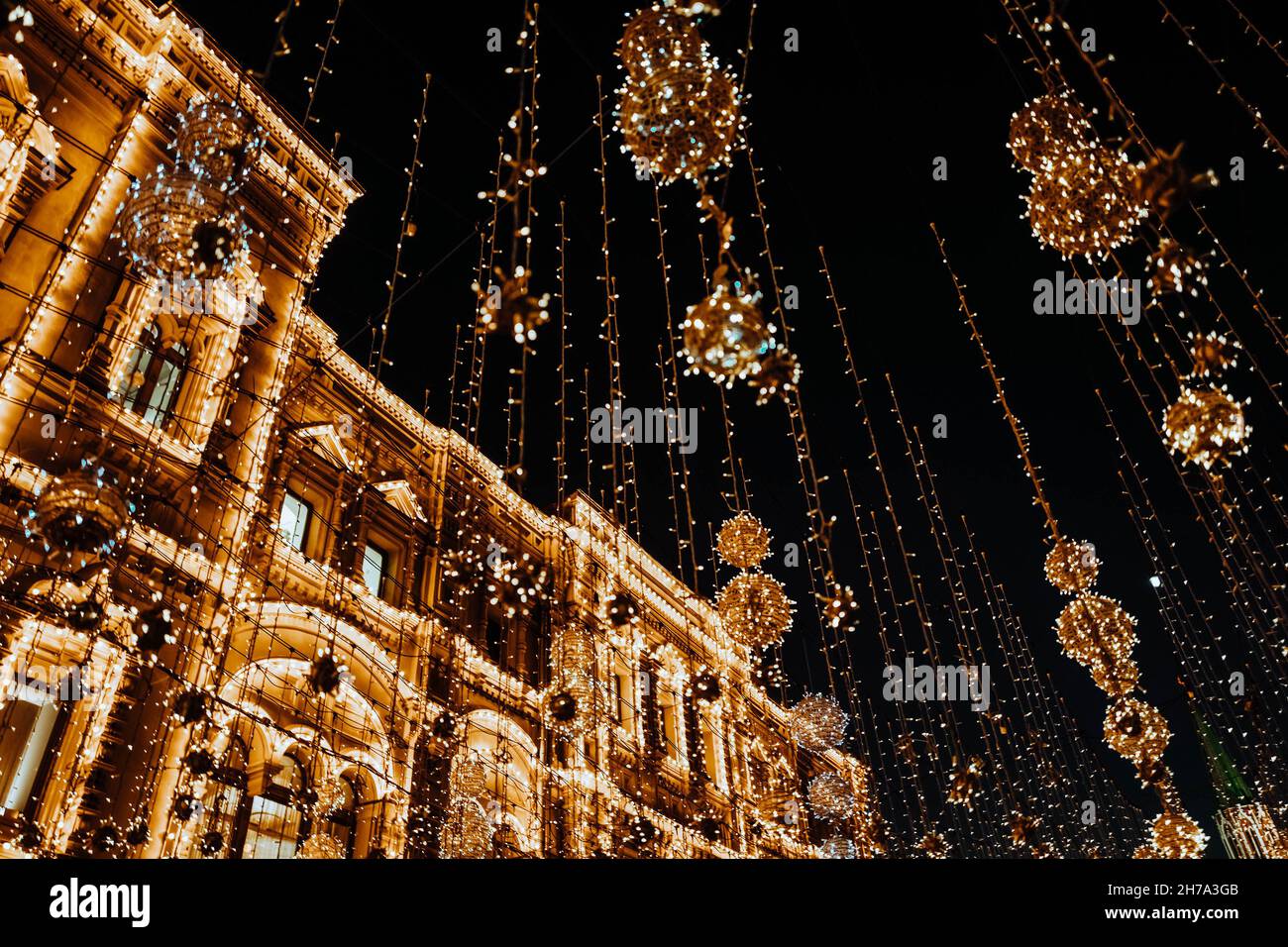 Vintage building decorated with golden glittering festive garlands. Christmas and New Year in the evening city Stock Photo