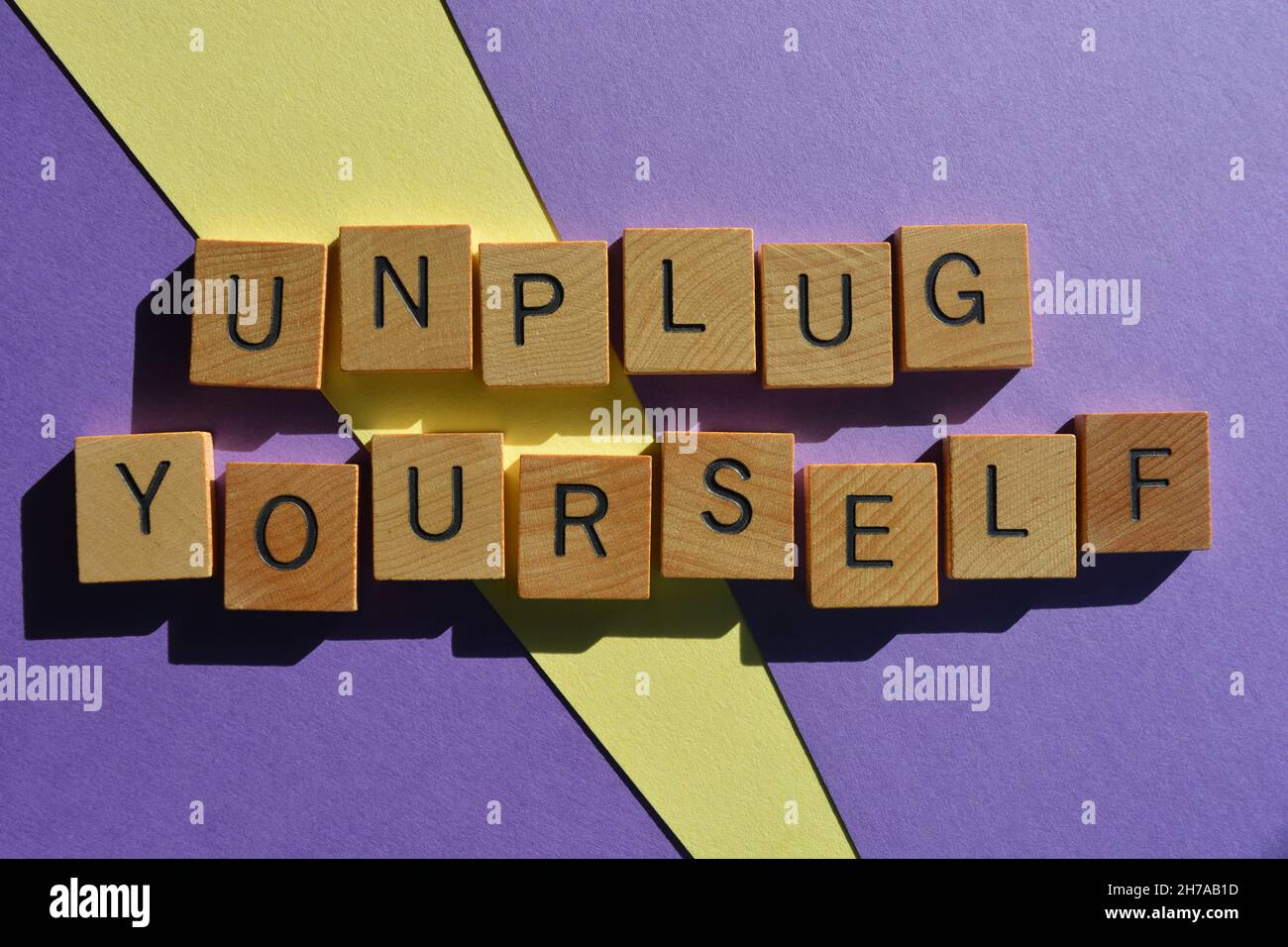 Unplug Yourself, words in wooden alphabet letters isolated on purple and yellow background Stock Photo