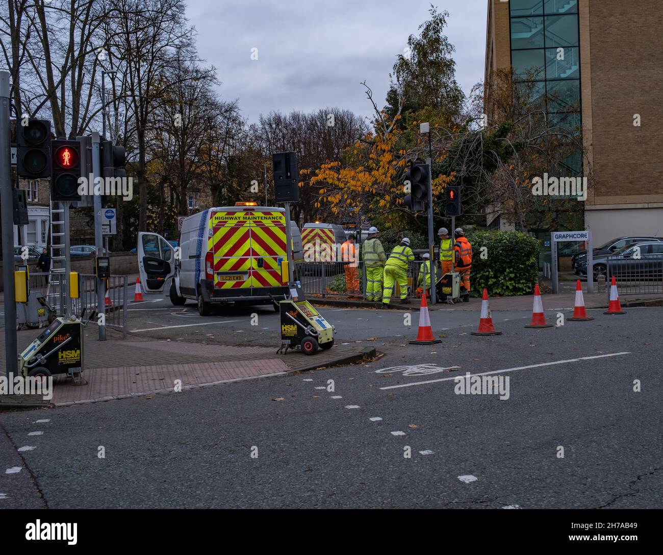 A group of workmen in hi-viz clothing and hardhats digging up the pavement and repairing the highway in the city of Cambridge, November 2021 Stock Photo
