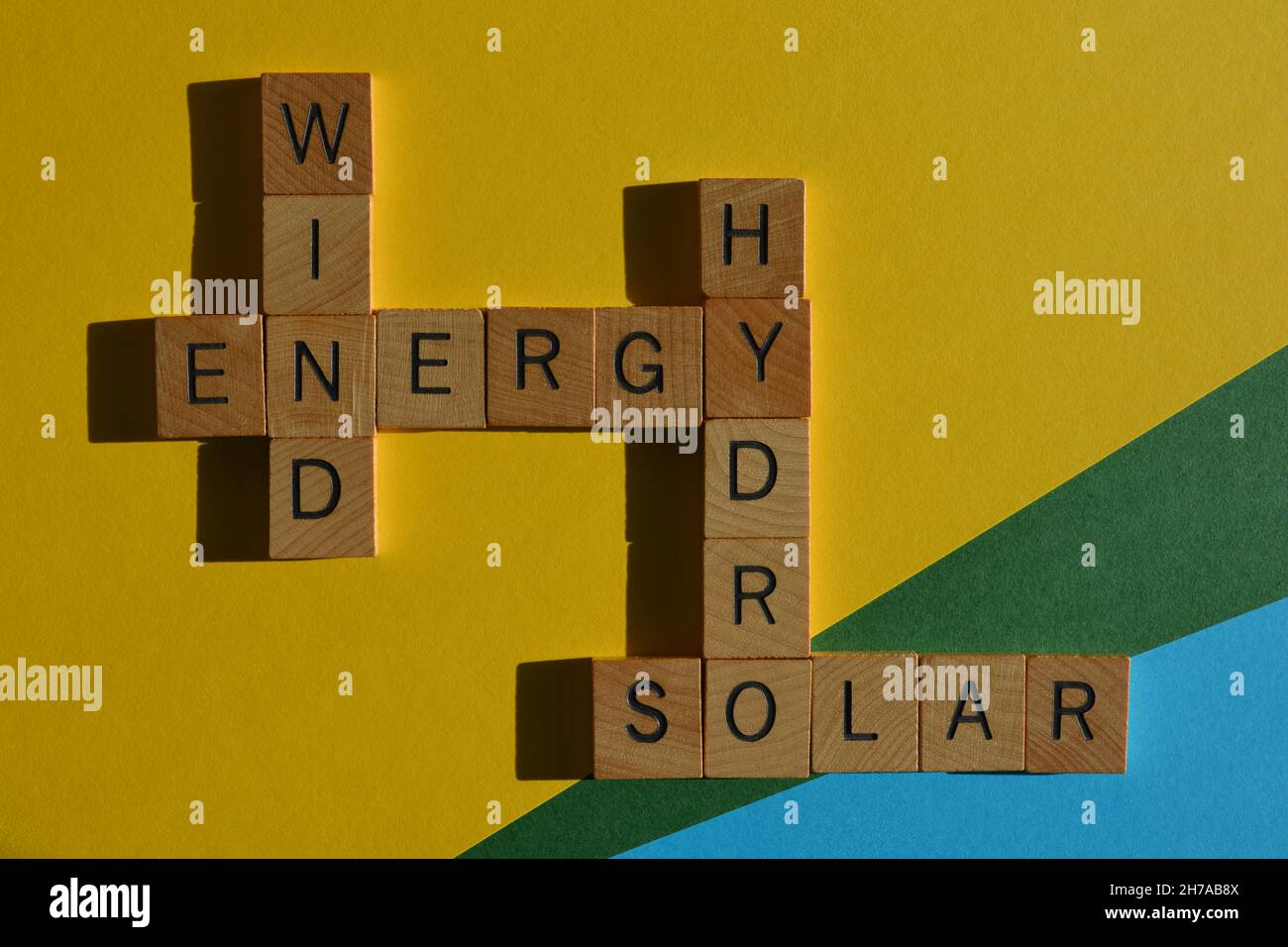 Energy, Wind, Hydro, Solar, words in wooden alphabet letters in crossword form isolated on yellow blue and green background Stock Photo