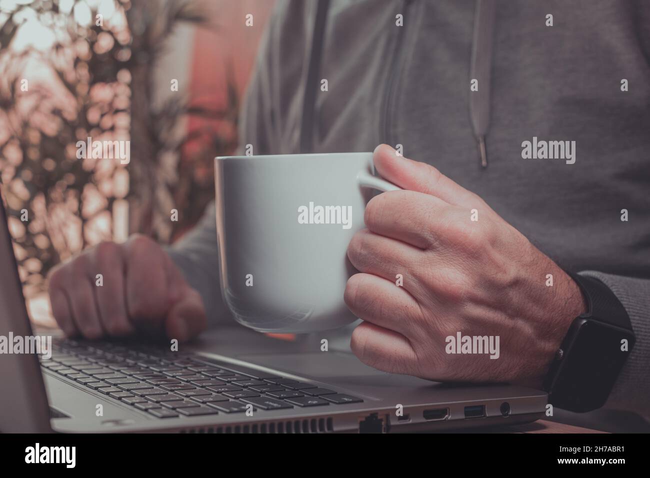 Freelancer is drinking coffee and working from home on laptop computer ...