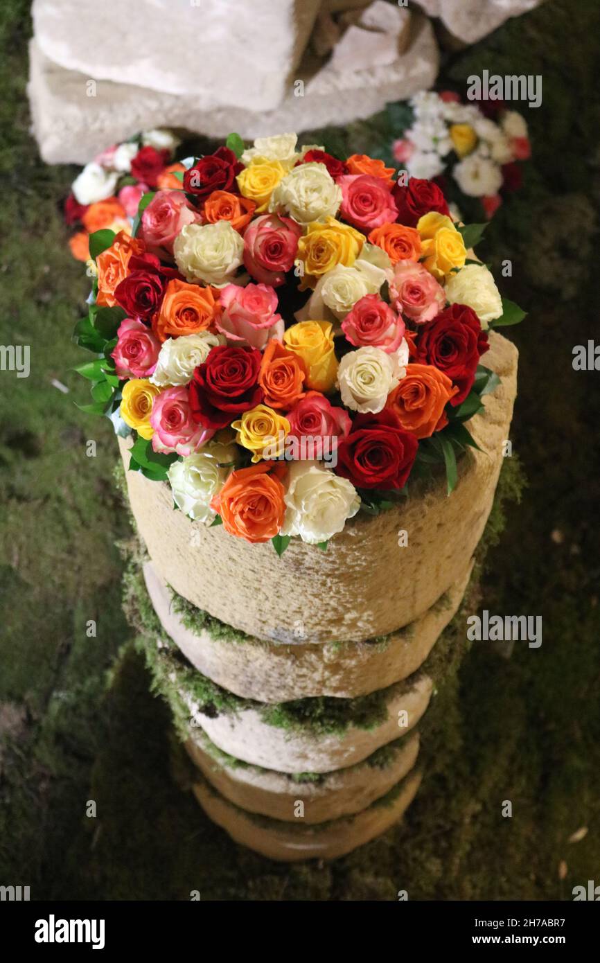 Bouquet of mixed roses displayed in an old stone pillar in a church in Hort de Sant Joan Stock Photo