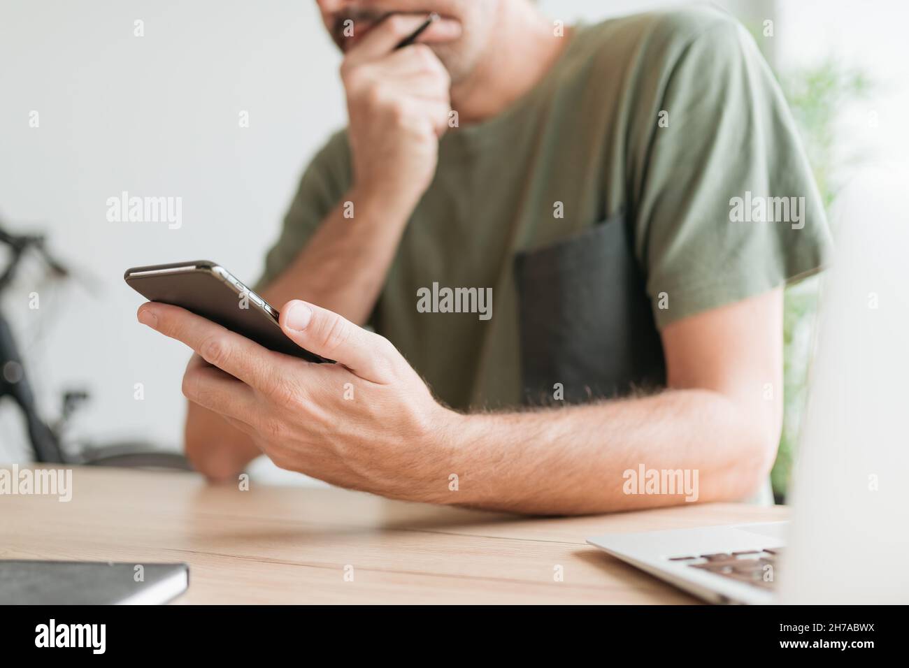 Telecommuter reading text message on mobile smart phone in home office, selective focus Stock Photo