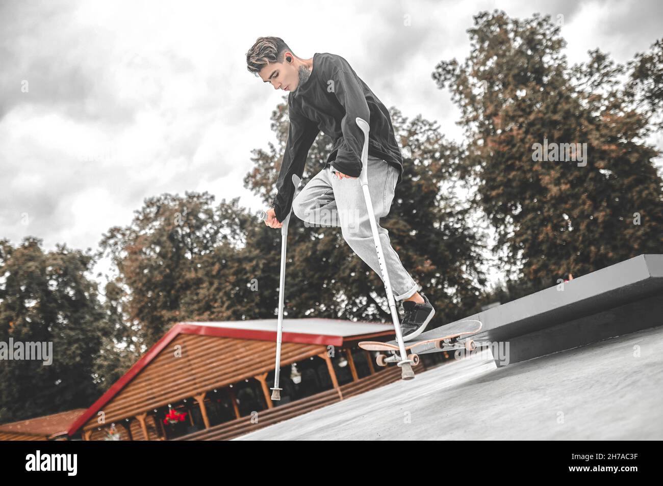 Disabled guy successfully jumping on skateboard from springboard Stock Photo