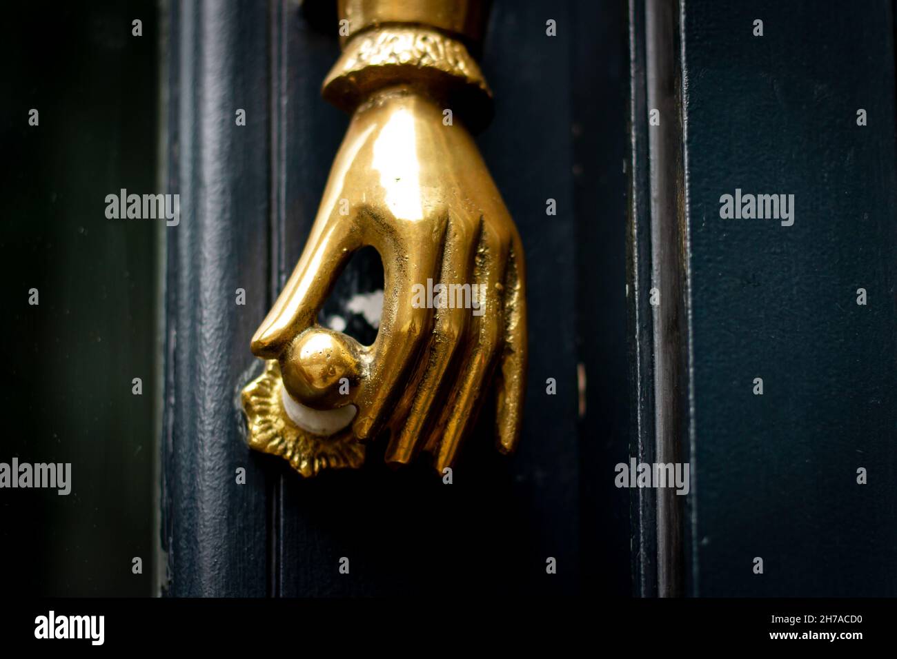Golden hand holding a door knob a a door knocker in London Stock Photo