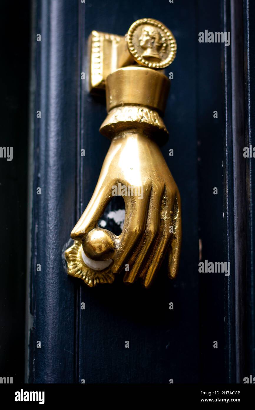 Golden hand holding a door knob a a door knocker in London Stock Photo