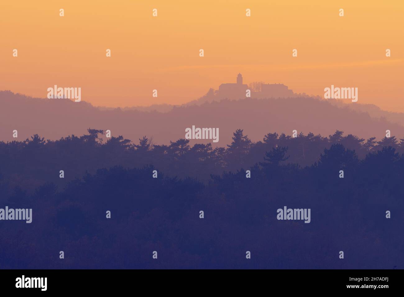 Beautiful view of treetops in layers and the Monrupino Church near Trieste in distance during twilight hour. Photo of Monrupino, Italy Stock Photo
