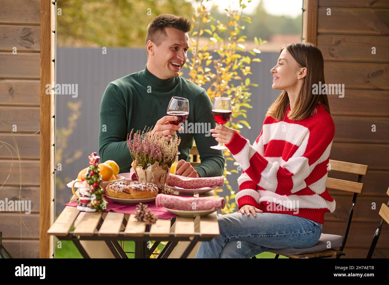 A couple sitting at the table with glasses of wine in hands Stock Photo