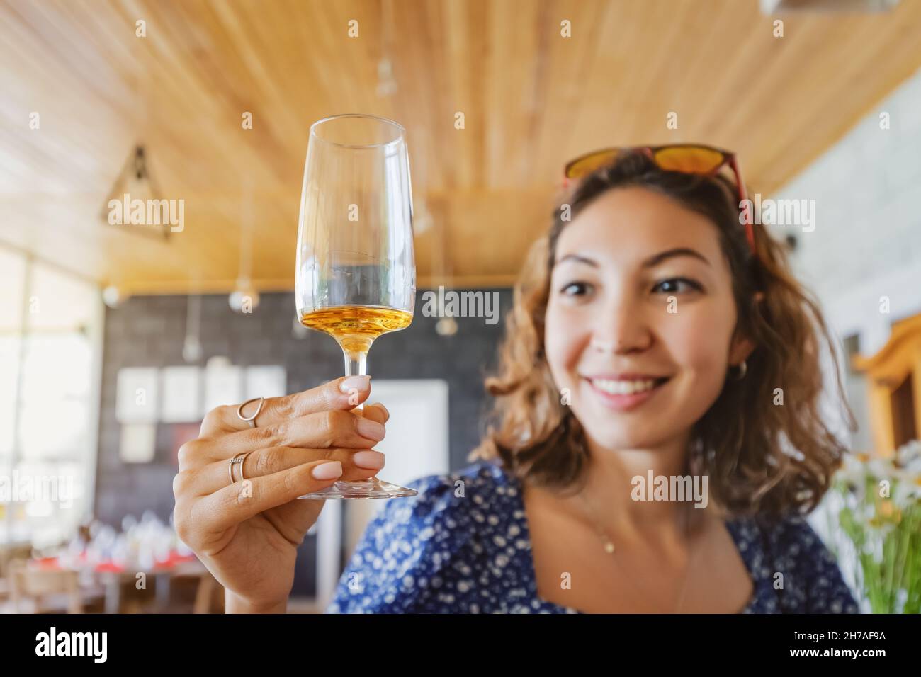 Happy asian woman tastes a new brand of cognac or grappa from a glass at the winery. The concept of strong alcohol and brandy Stock Photo