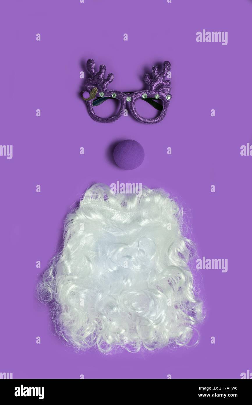 Christmas concept with funny purple glasses and Santa beard on ultra violet background. Funny face flat lay Stock Photo