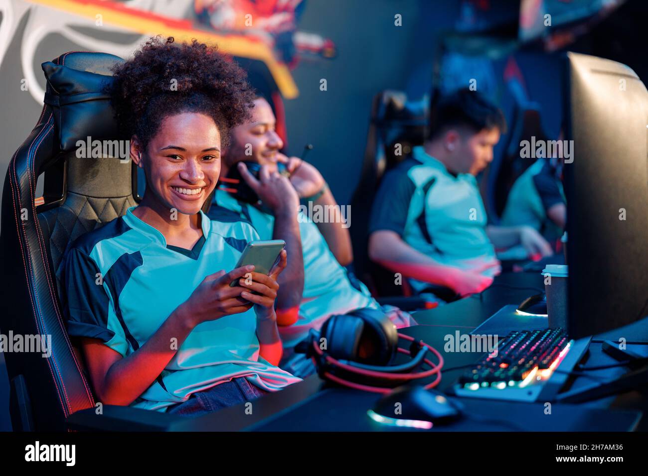 Happy woman plays online video games professionally in internet cafe Stock Photo