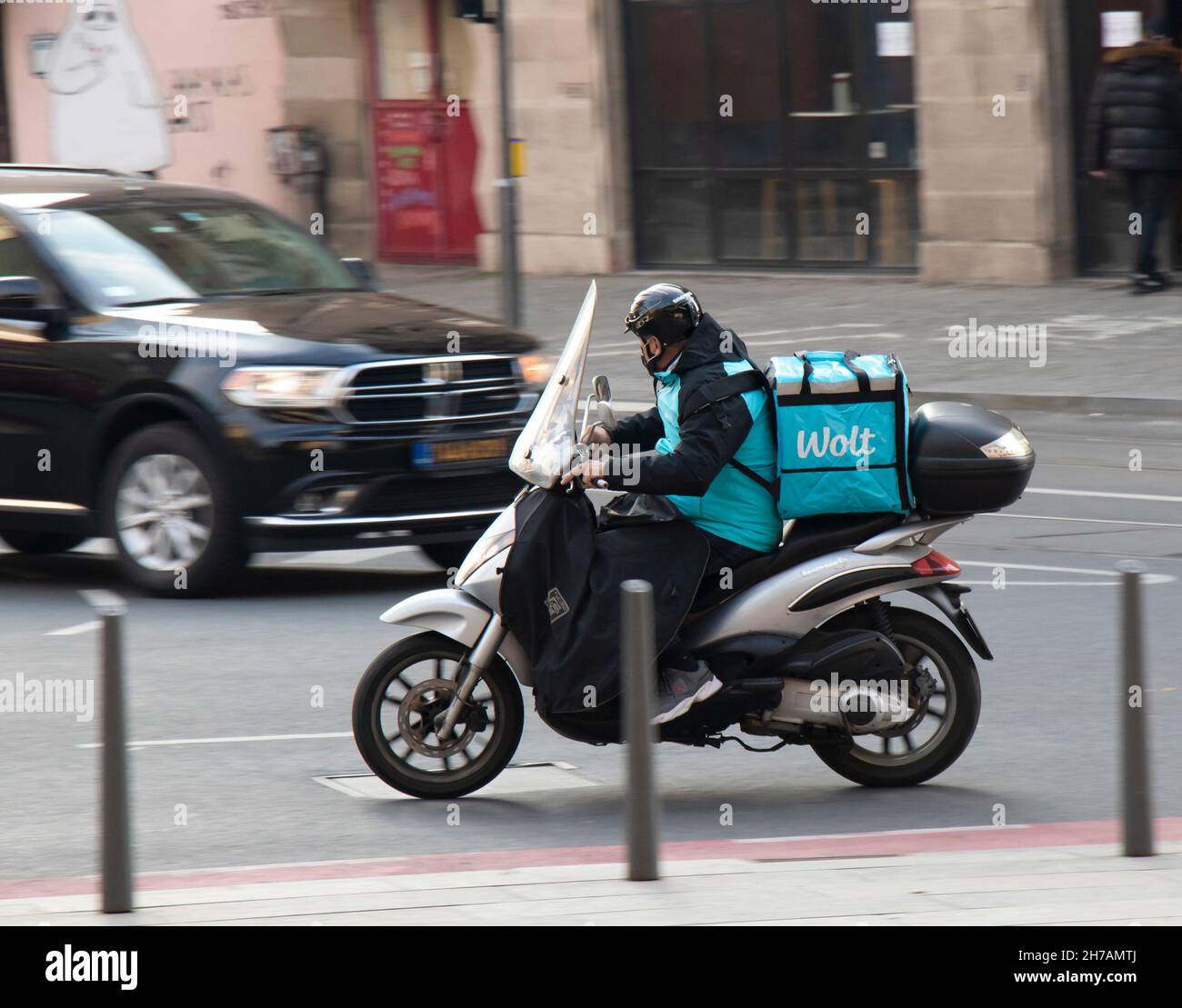 Belgrade, Serbia - November 17, 2021: Person working for city food delivery service Wolt riding a scooter on busy city street Stock Photo