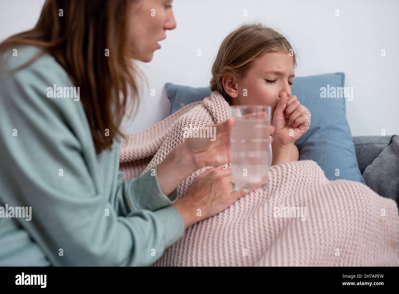 Mother puts a fizzy tablet in the water and gives this drink to her sick daughter Stock Photo
